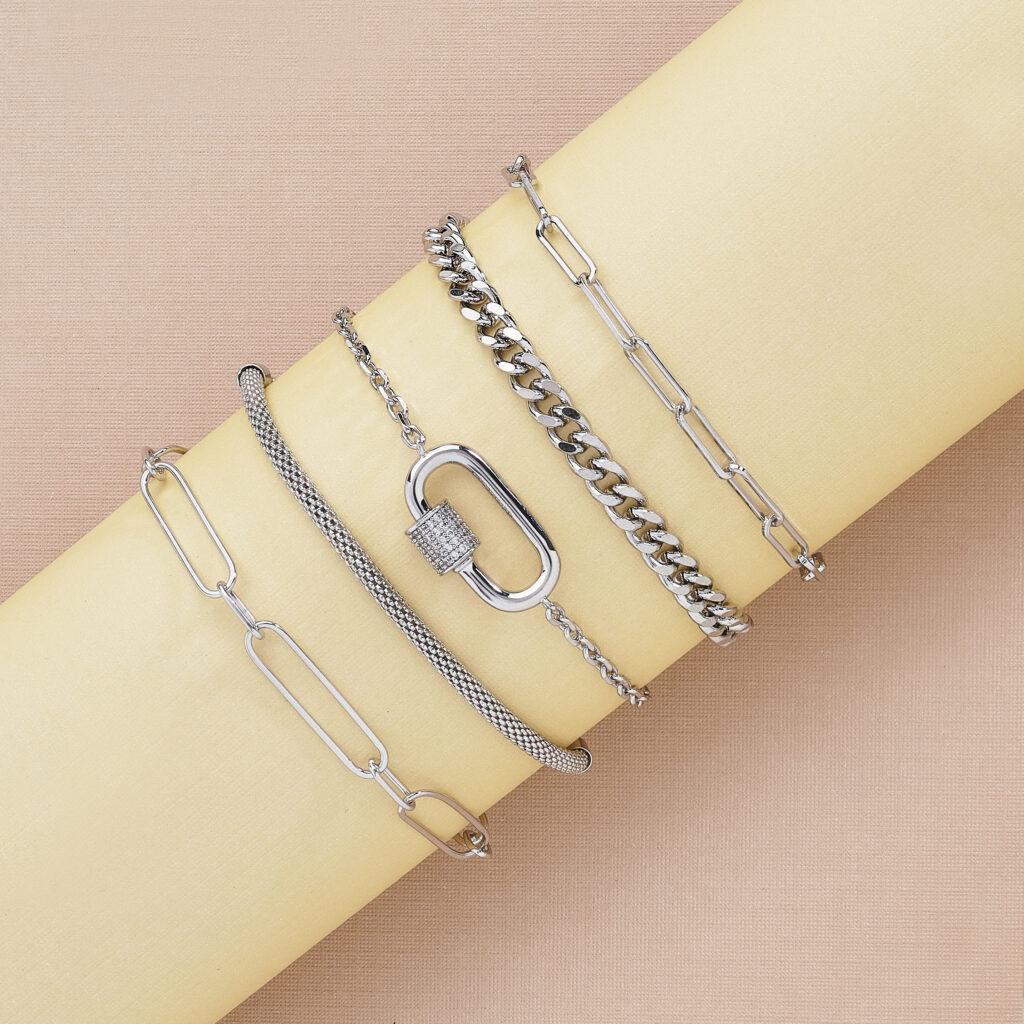 assorted silver bracelets on buff colored background with soft lighting