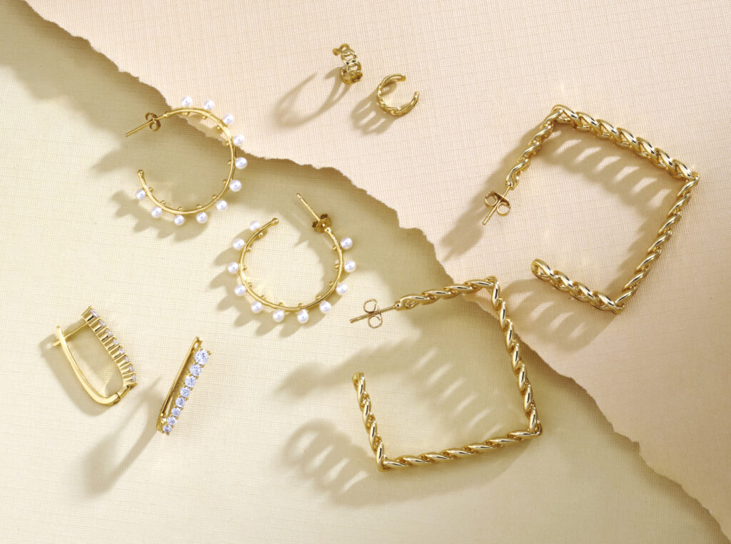 gold jewelry assortment on a colorful background with dramatic shadows