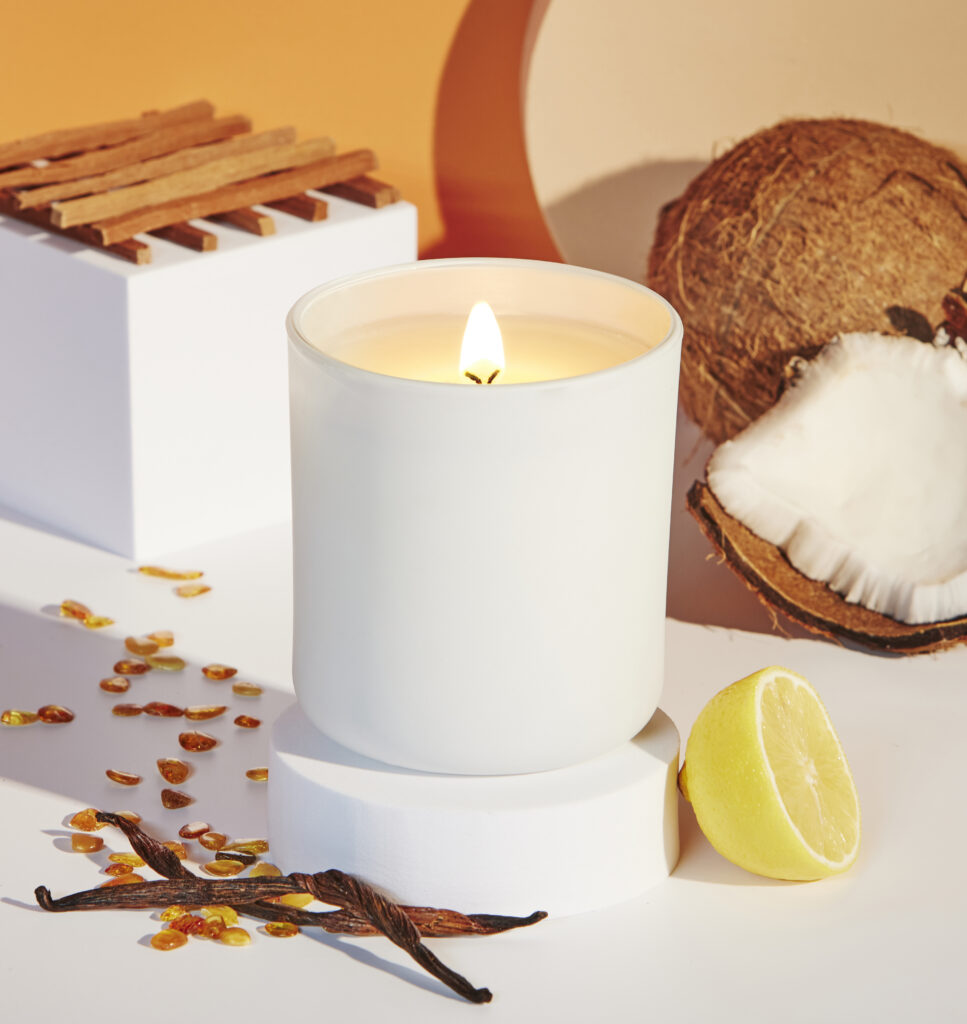 Cue Candle Company white candle in clean white tropical scene with coconut