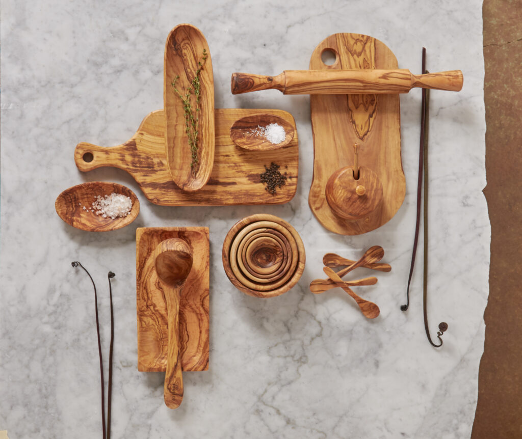 various olive wood bowls boards and utensils on marble surface
