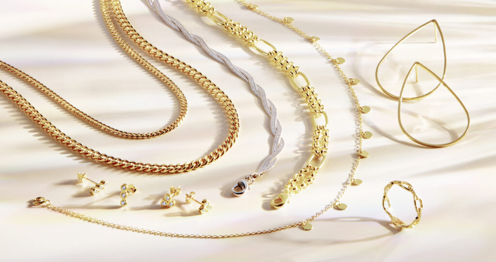 gold and silver jewelry with dramatic shadows on neutral background