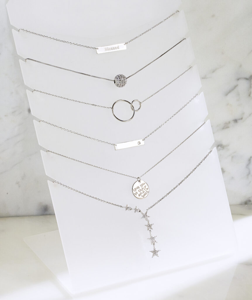 assorted silver pendants on white display form