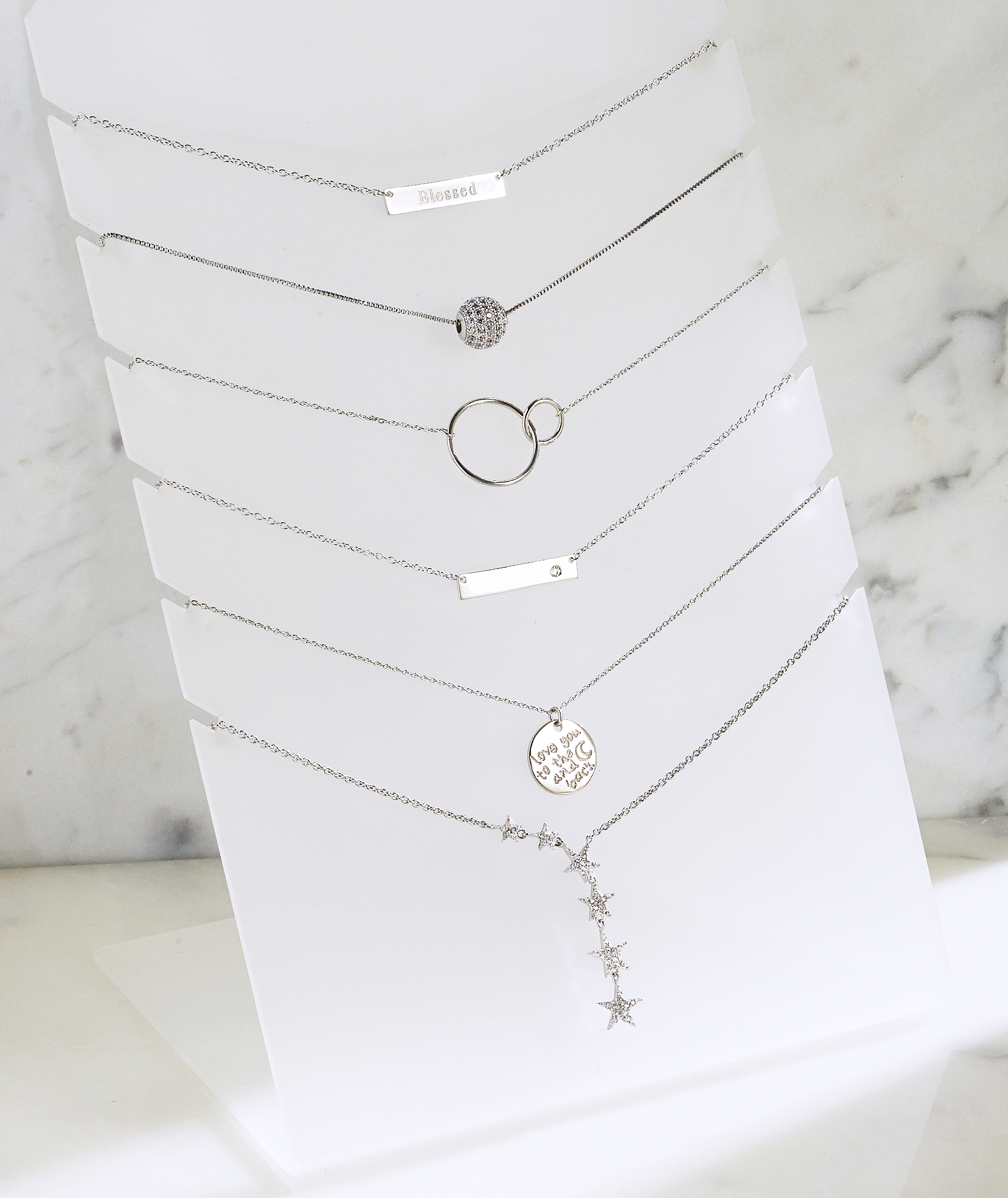 assorted silver pendants on white display form