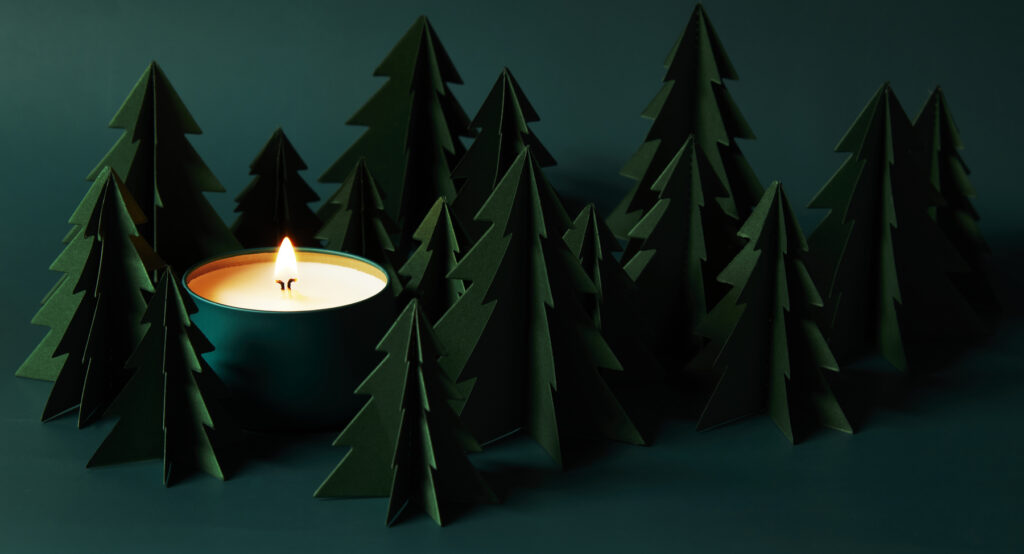deep green forest of paper pine trees with deep green votive glowing yellow