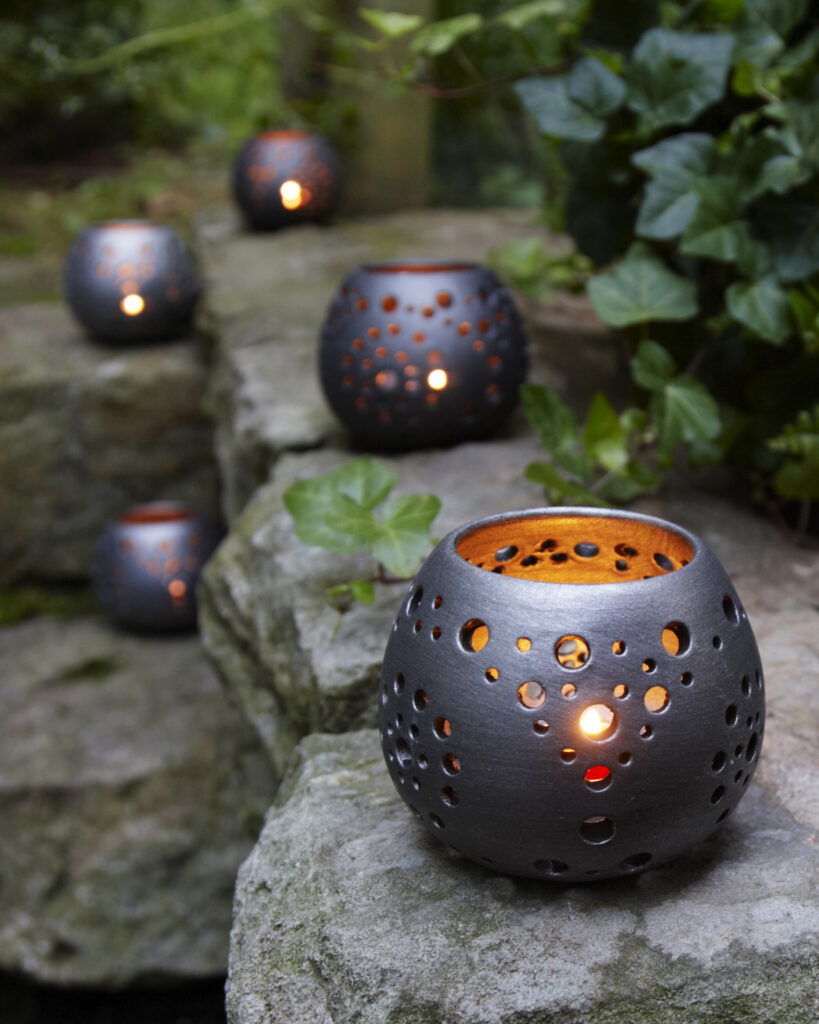 fair trade ceramic votives aglow on a garden wall at dusk
