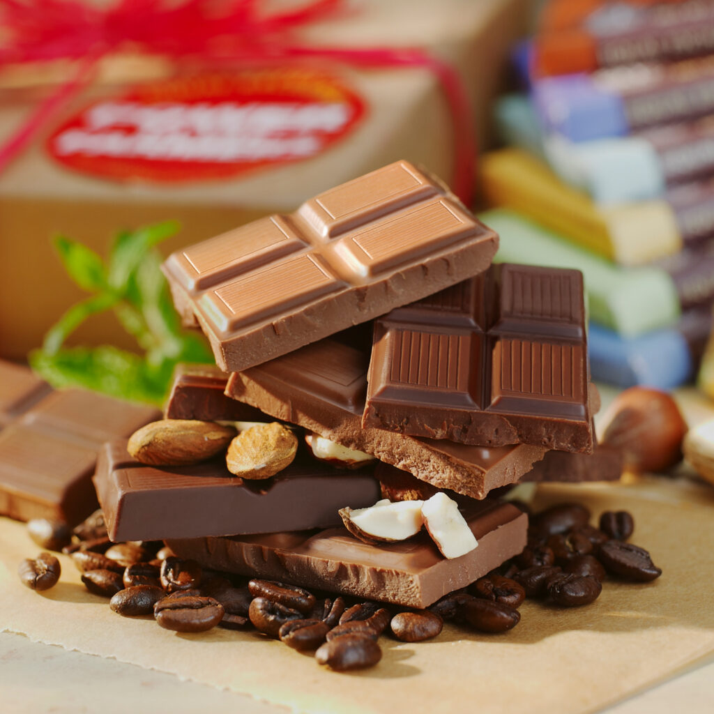 yummy stack of brokrn chocolate bars with nuts and coffee beans