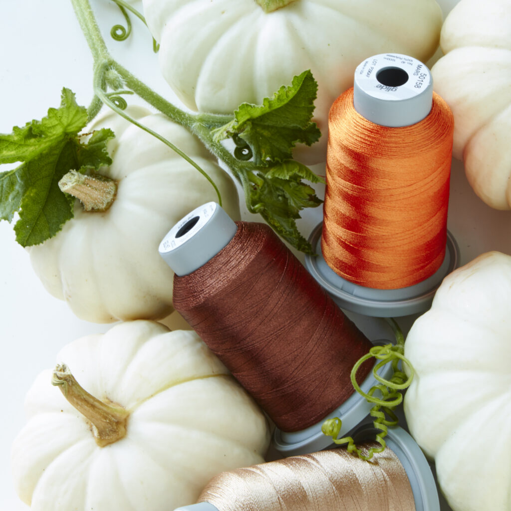 brown and orange thread spools on white pumpkins