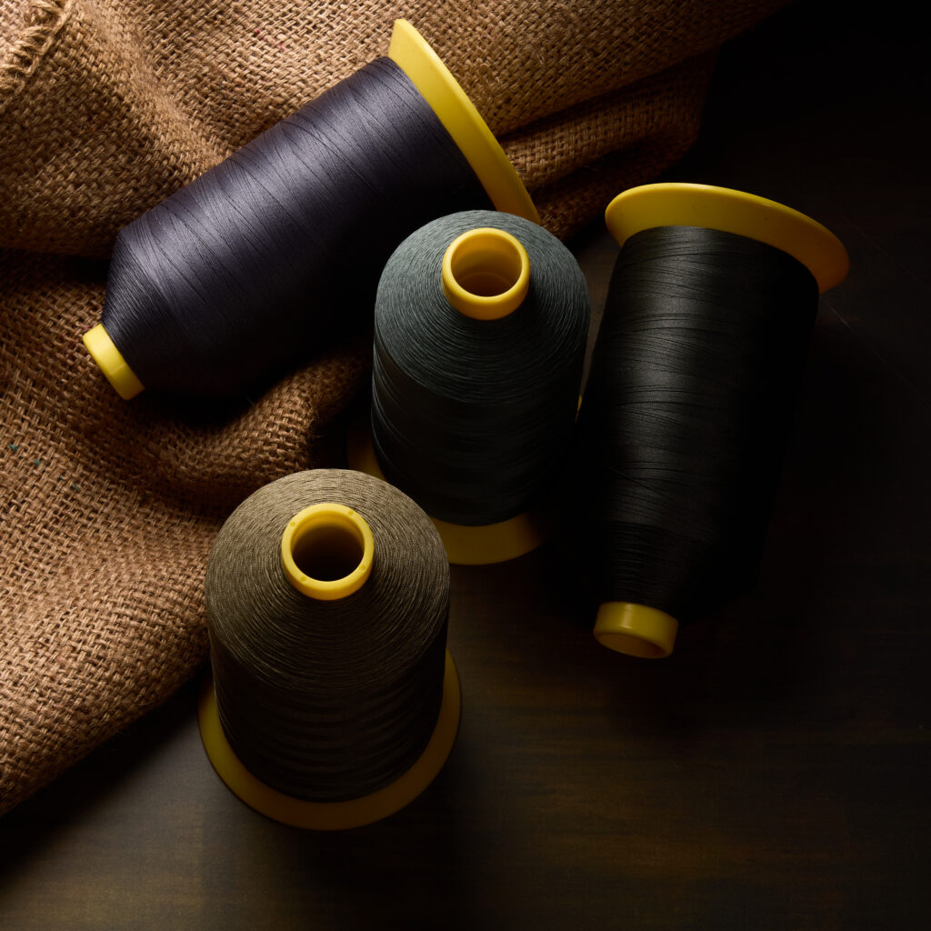 spools of dark thread on burlap with dramatic lighting