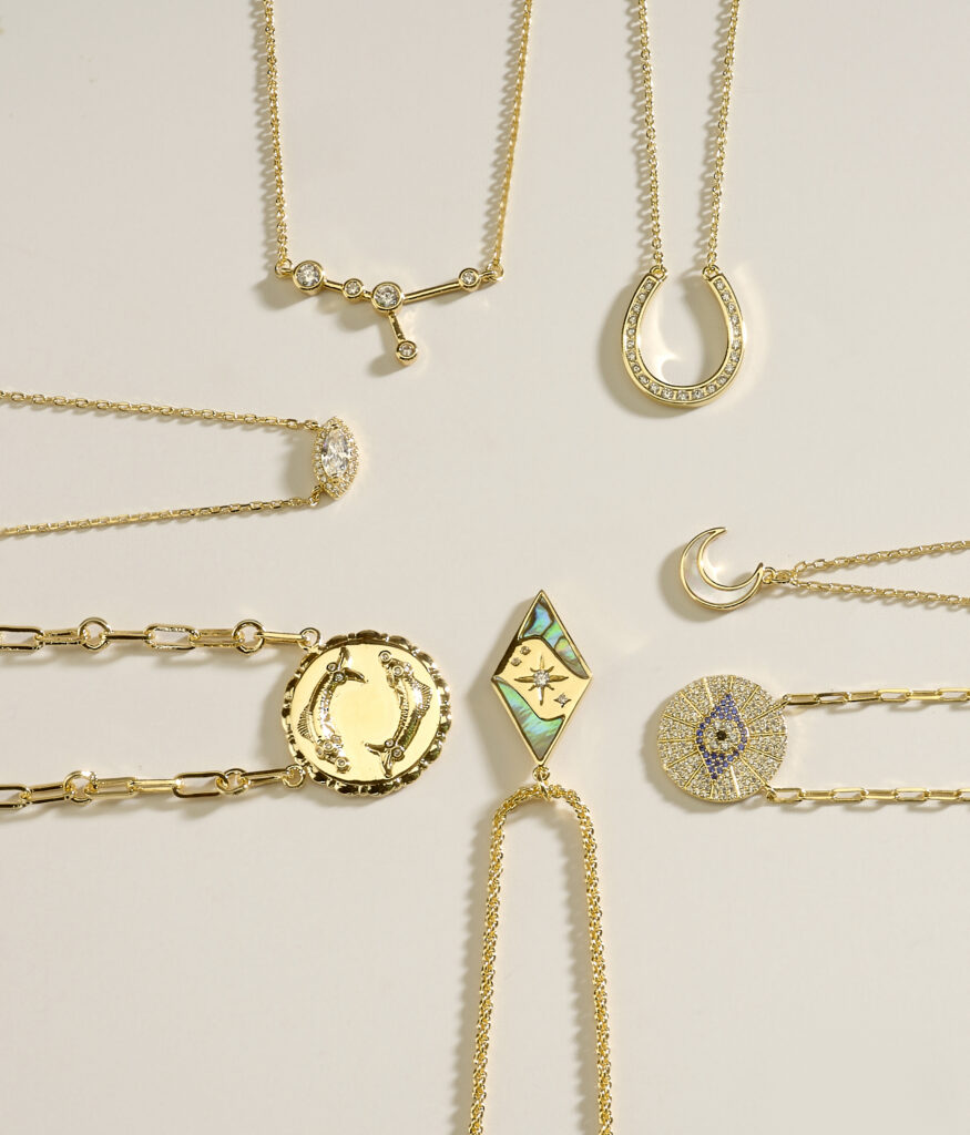assorted gold pendants on neutral colored background with dramatic lighting