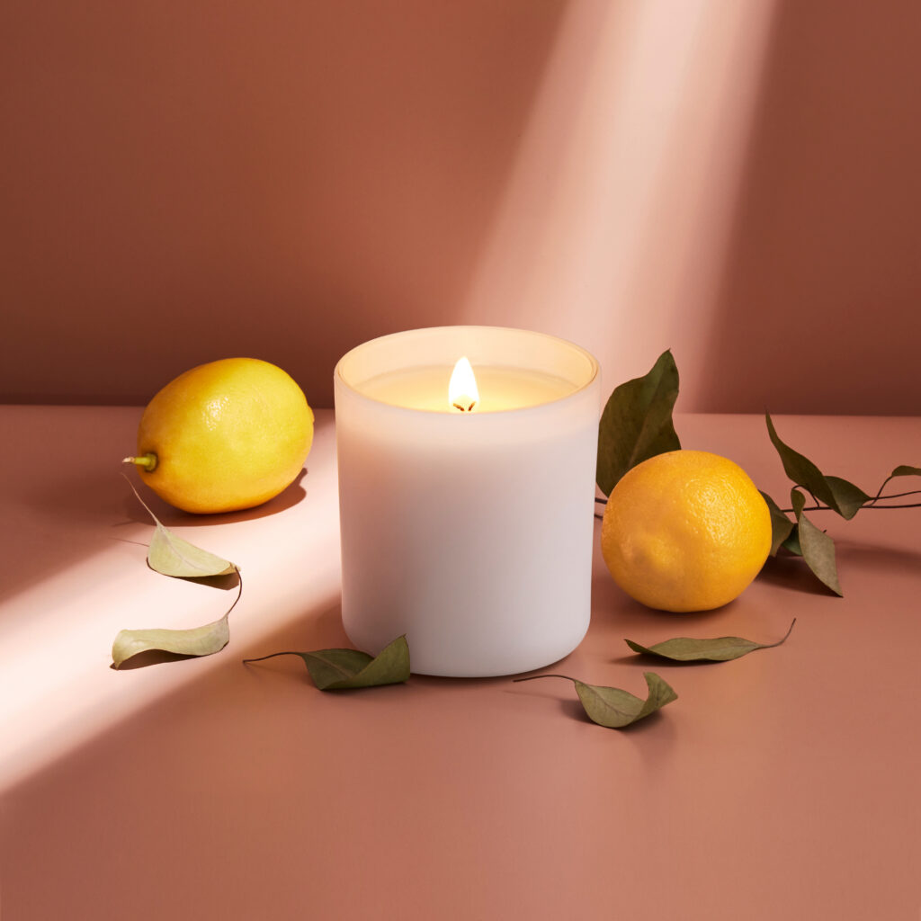 Cue Candle Company white candle jar on buff background with lemons and dramatic light