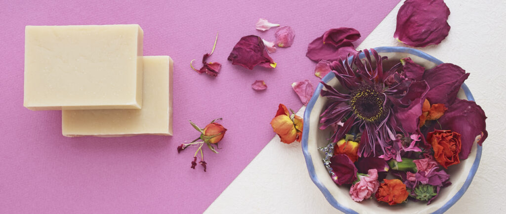 hand crafted soaps on colorful background with scattered botanicals