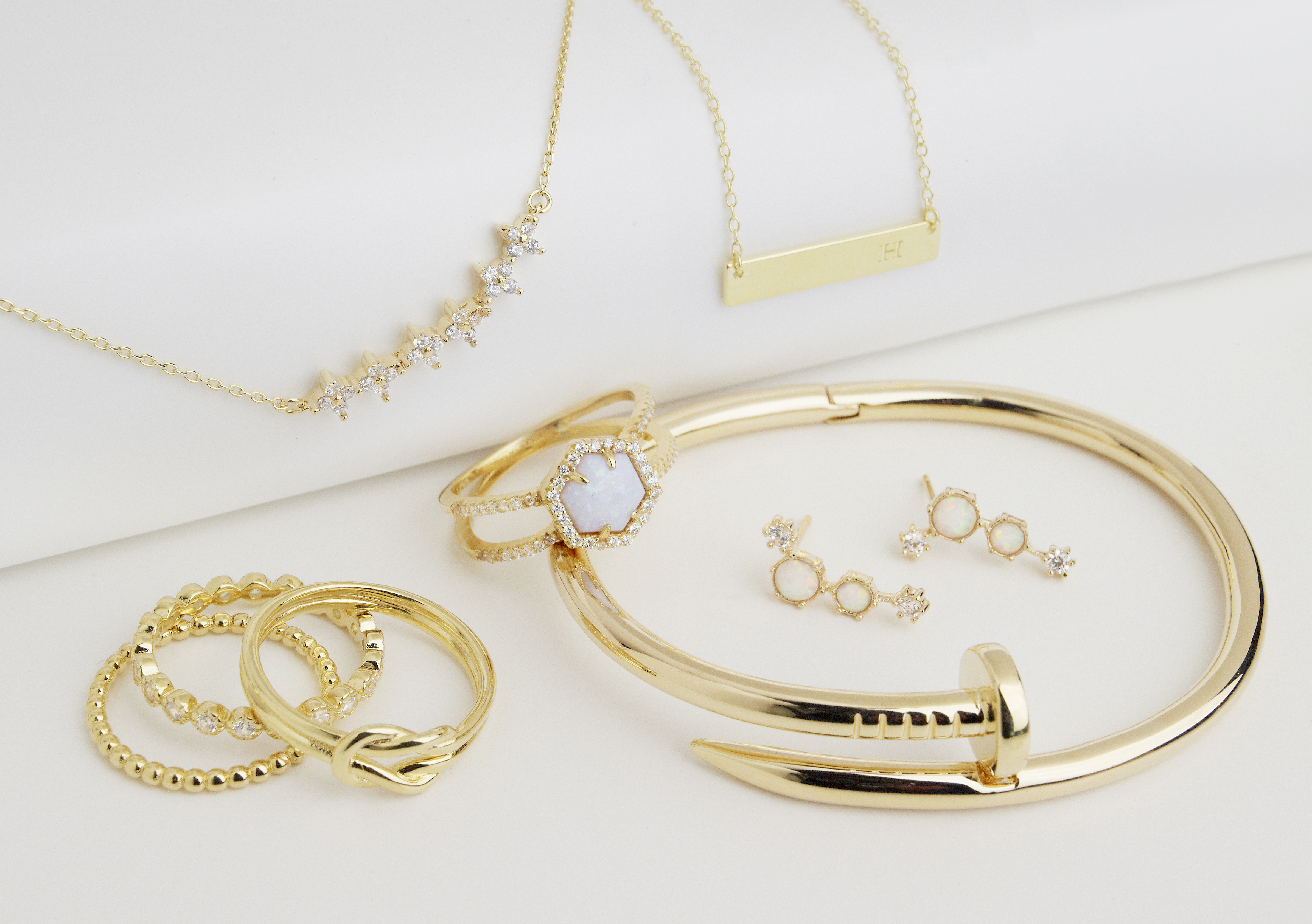 assorted opal gold and silver jewelry with dramatic shadows