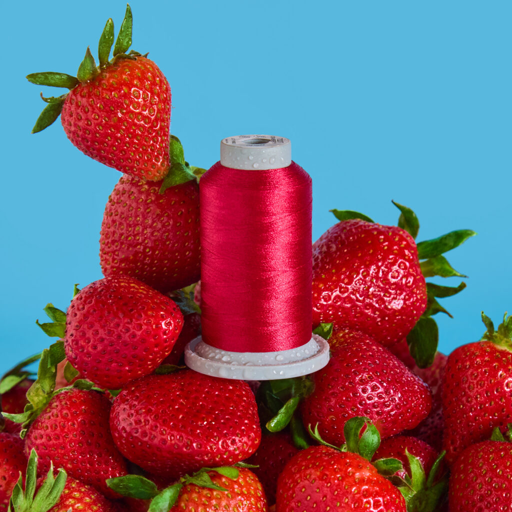bright red thread on a pile of strawberries