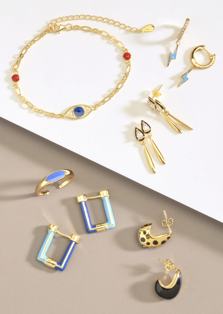 assorted gold and enameled jewelry neutral colored background with dramatic lighting