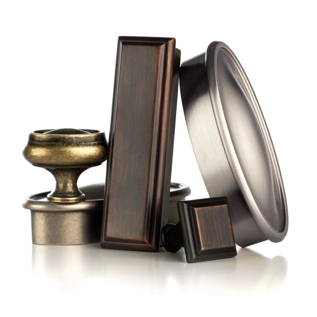 Amerock Manor oil rubbed bronze aged bronze and satin nickel hardware arranged as sculpture on white background