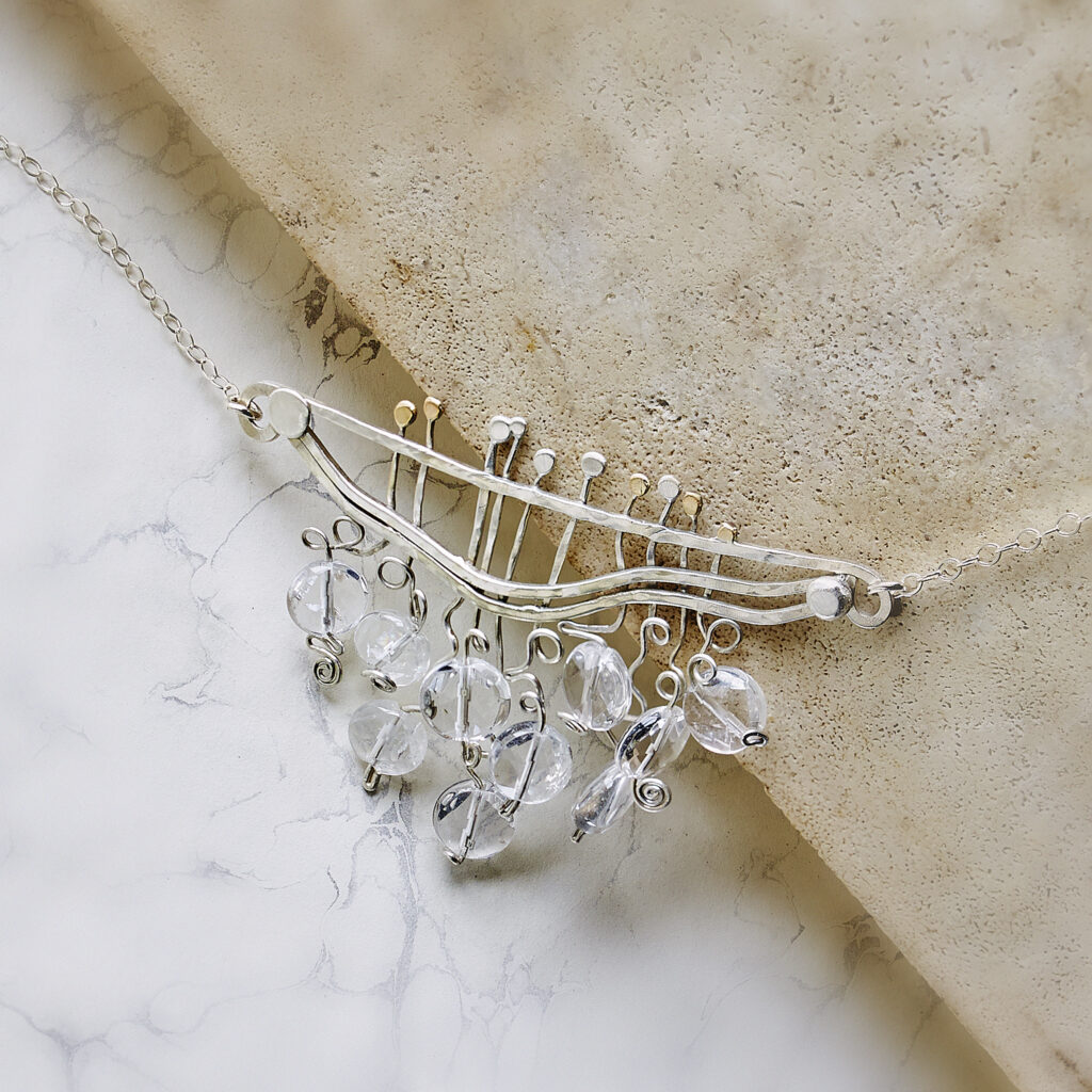 handcrafted silver and clear beaded pendant on a marble background