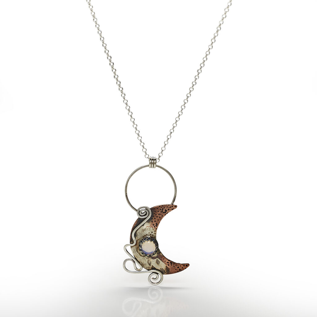 handcrafted silver pendant on white background with reflection