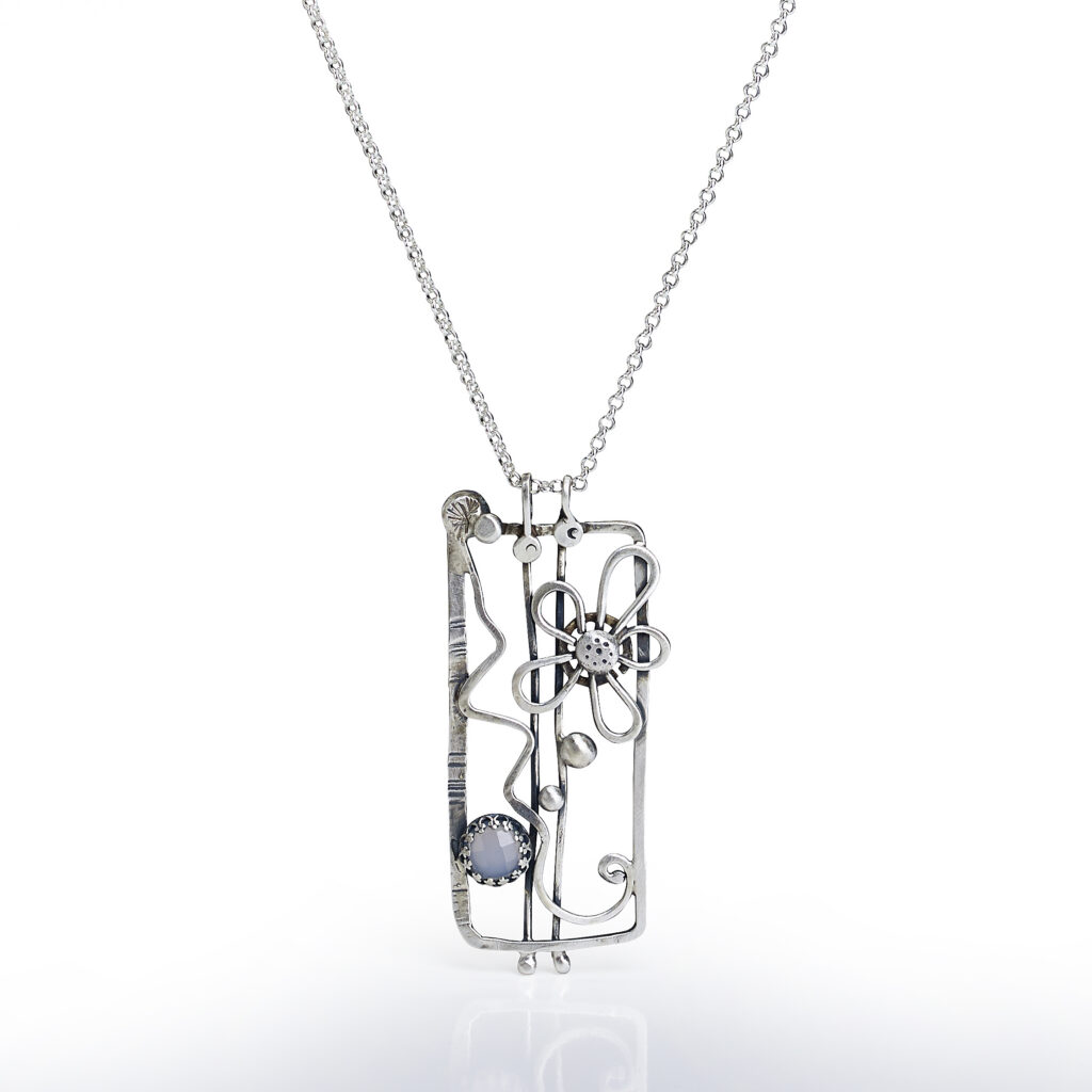 handcrafted silver pendant on white background with reflection