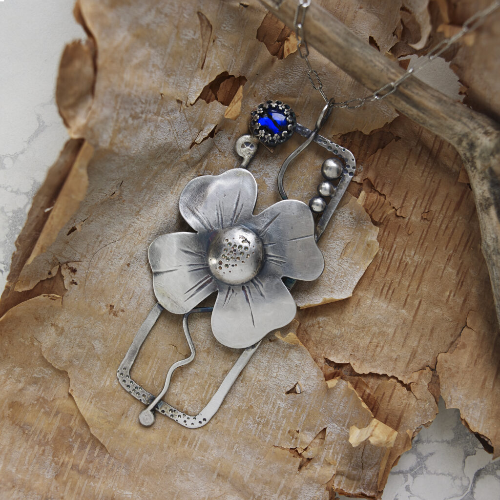 handcrafted silver and blue beaded pendant on a rustic background