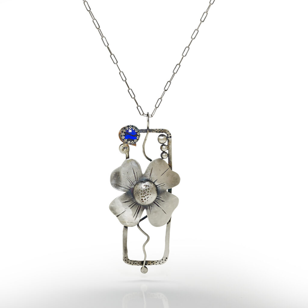 handcrafted silver pendant on white background with reflection