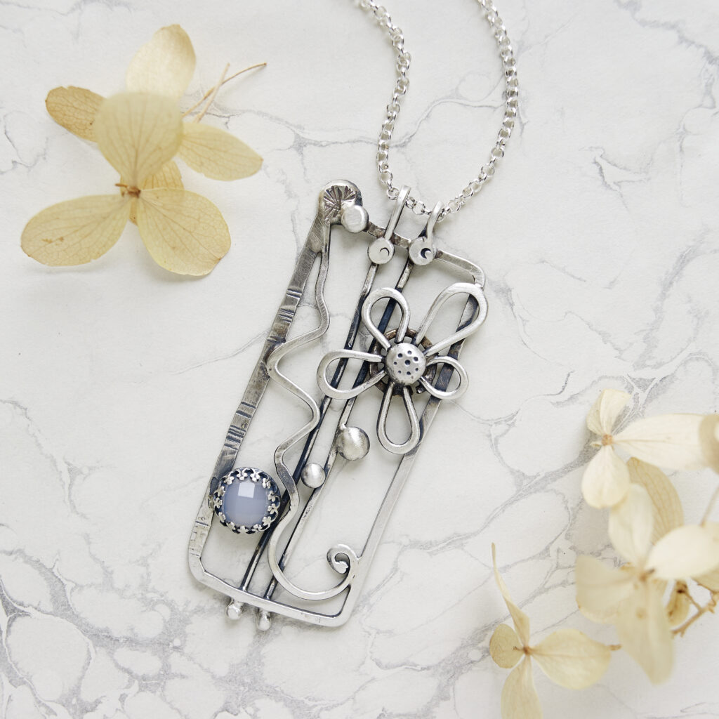 handcrafted silver and beaded pendant on a marble background