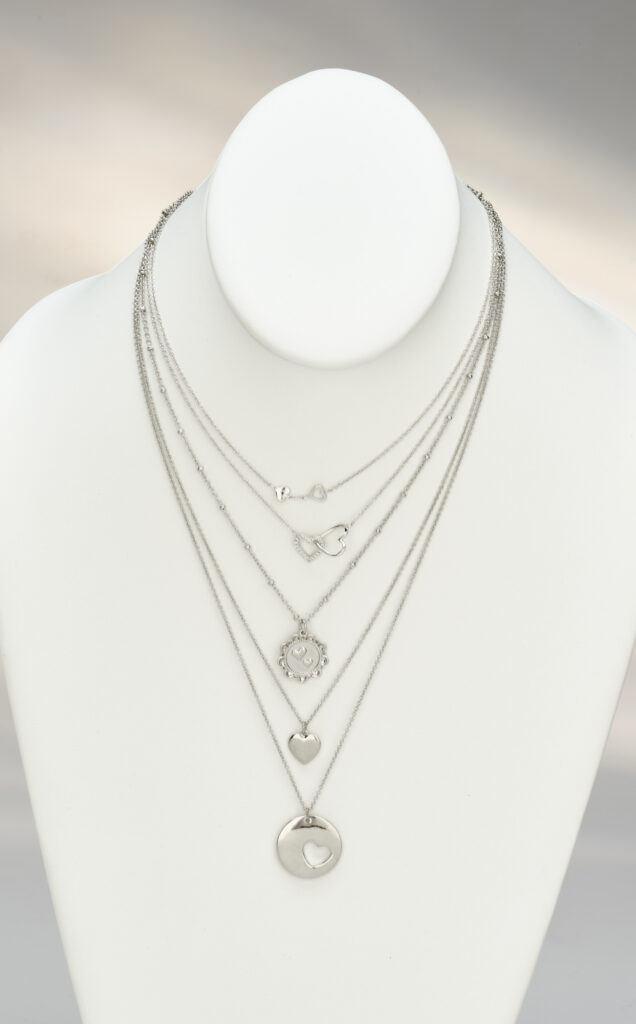 assorted silver pendants on white neck form