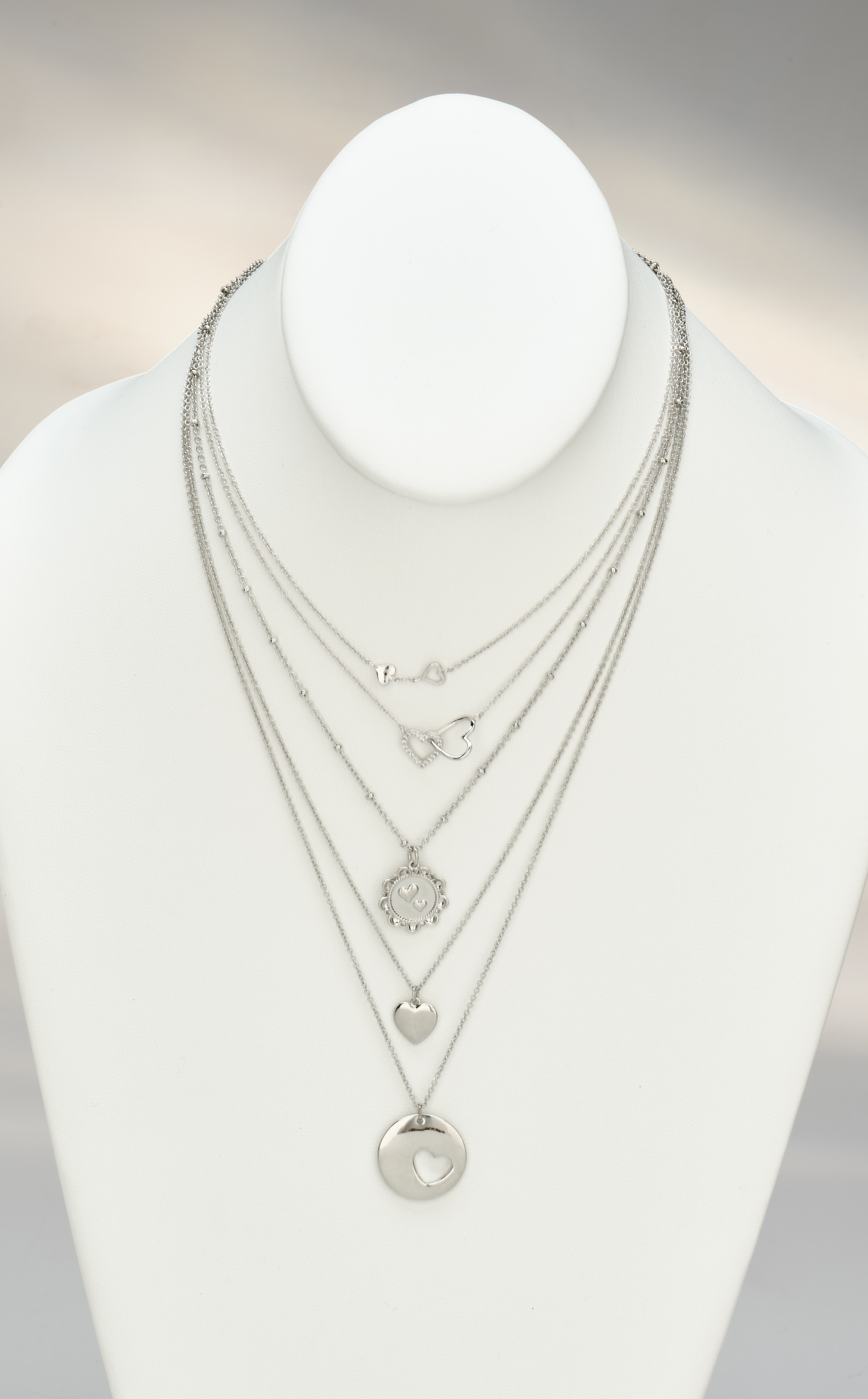 assorted silver pendants on white neck form