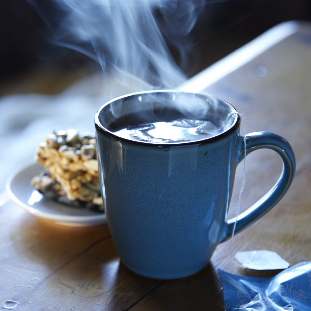 dramatic blue mug of steaming tea and breakfast cookie