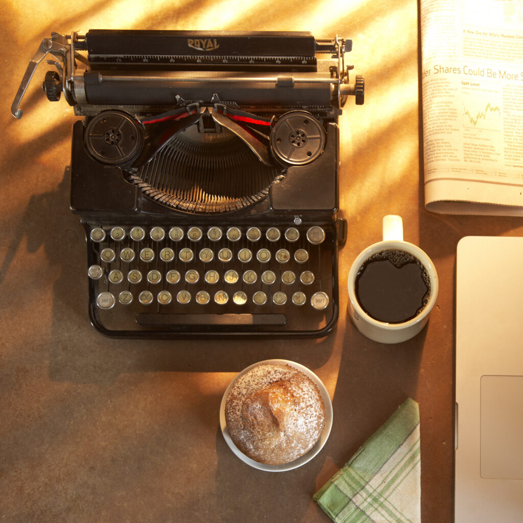 Old fashioned typewriter with coffee and muffin