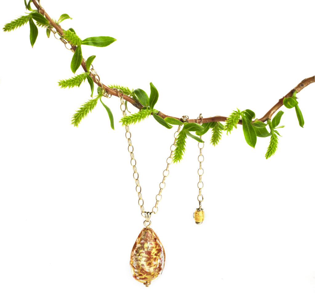 beautiful amber pendant hanging on willow branch on clean white background