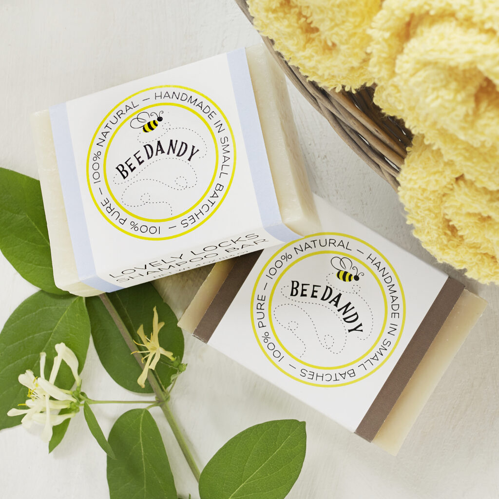 BeeDandy hand crafted soaps on light neutral background with scattered botanicals