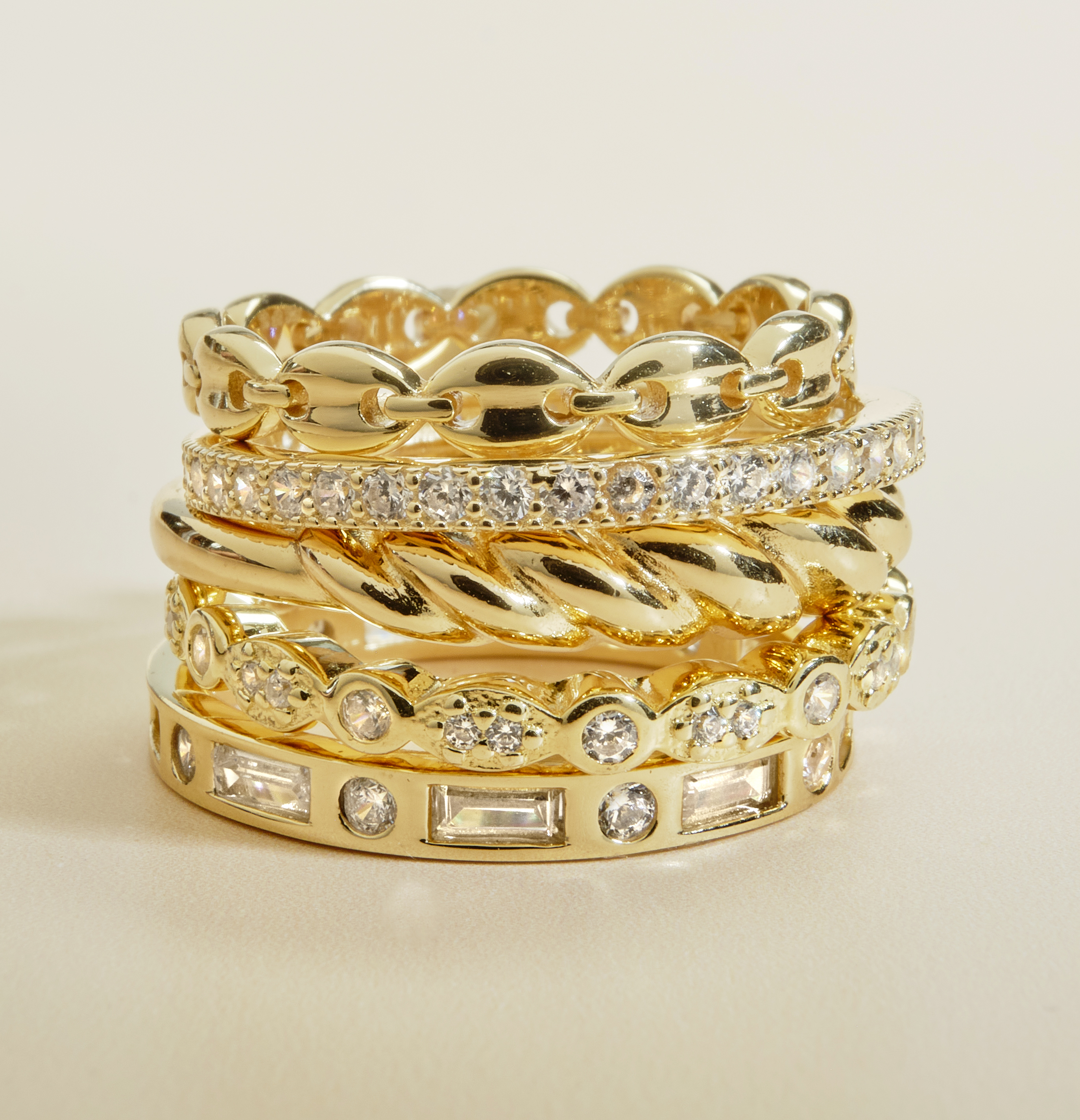 gold and diamond rings in stack on neutral background