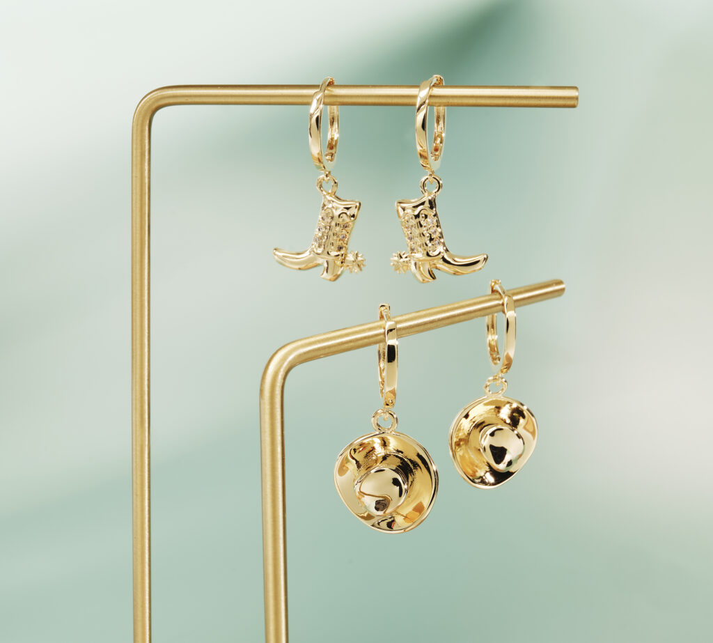 gold earrings with a cowboy theme on a green backgorund