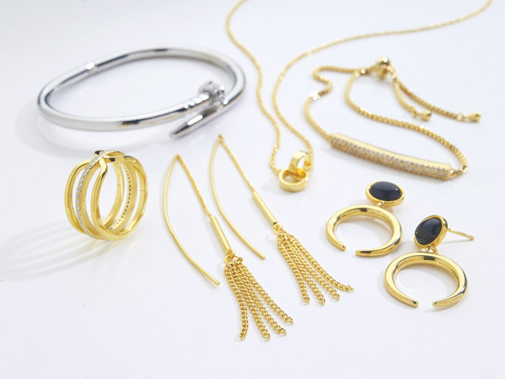 assorted gold and silver jewelry with dramatic shadows