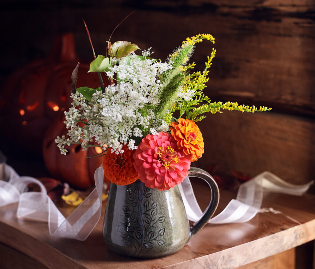 fall flowers arranged in fair trade mug in fall setting with clay pumpkin lanterns