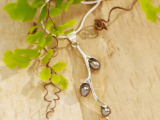 beautiful seed pearls in silver setting with lush fern and warm wood background