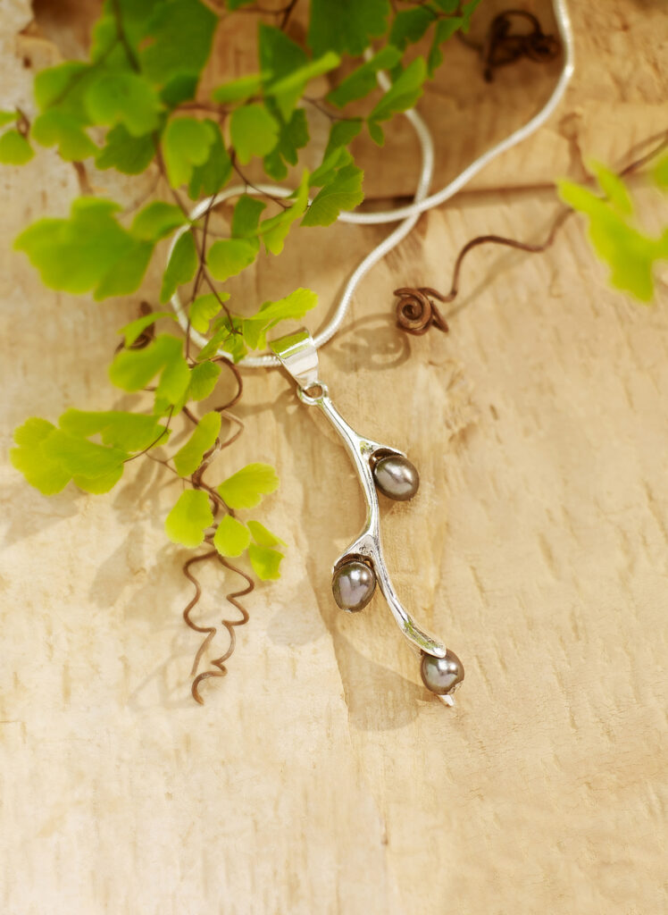 beautiful seed pearls in silver setting with lush fern and warm wood background