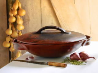 luminous clay vessel for paella with fresh herbs and rustic background