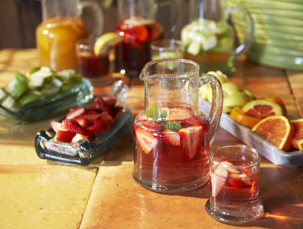 Fair trade hand blown glass pitcher filled with sangria with lots of fruit and colorful background