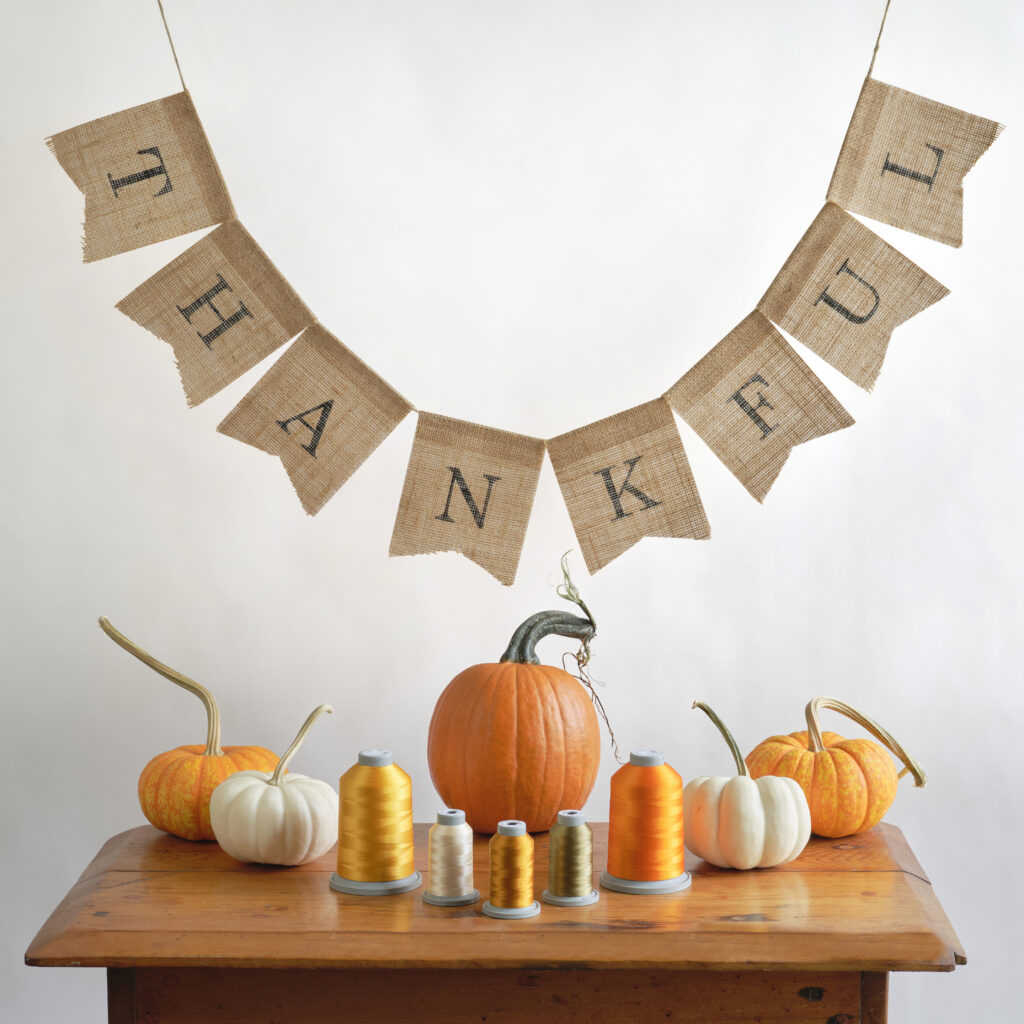thankful banner above a table with fall colored threads and pumpkins