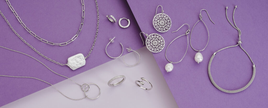 assorted silver and pearl jewelry on colorful purple background