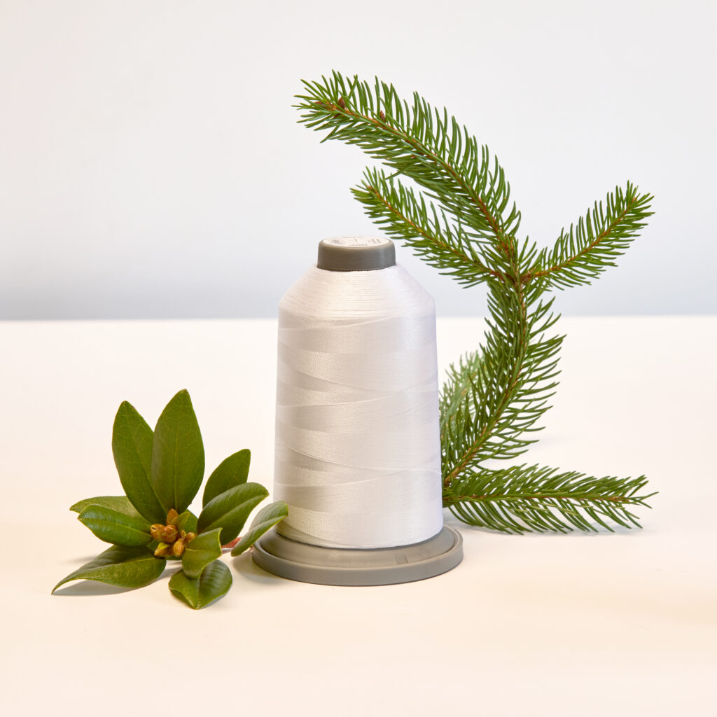 spool of white thread with holiday greens on neutral background