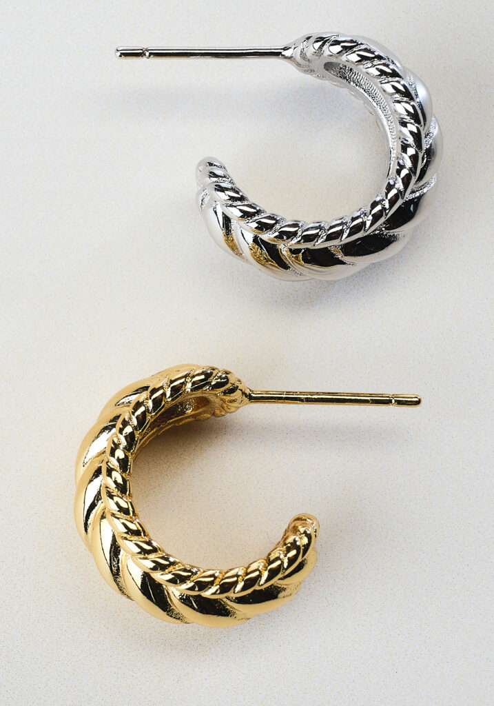 gold and silver earrings on neutral background with soft shadows