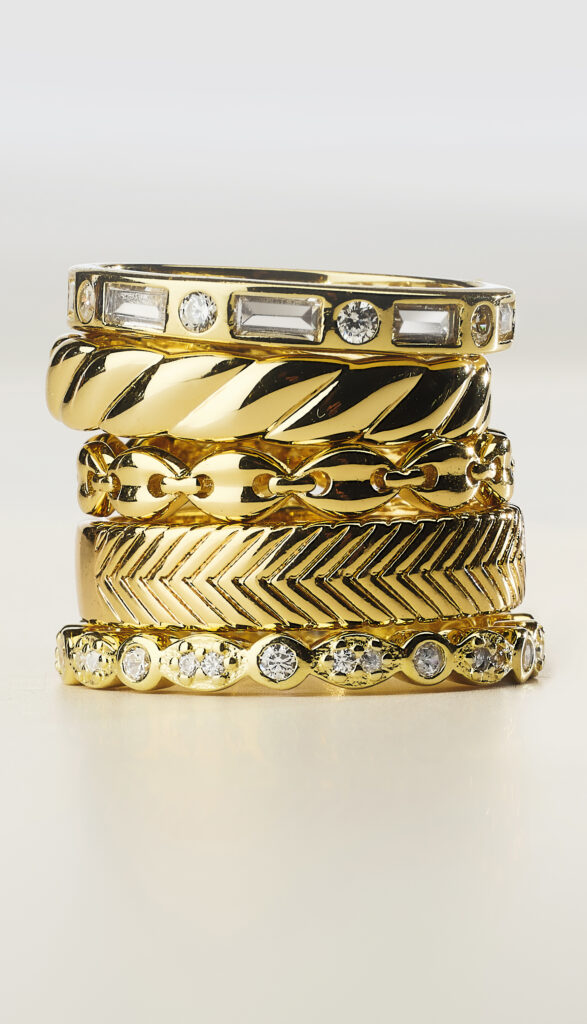 gold and diamond rings in stack on neutral background from low point of view