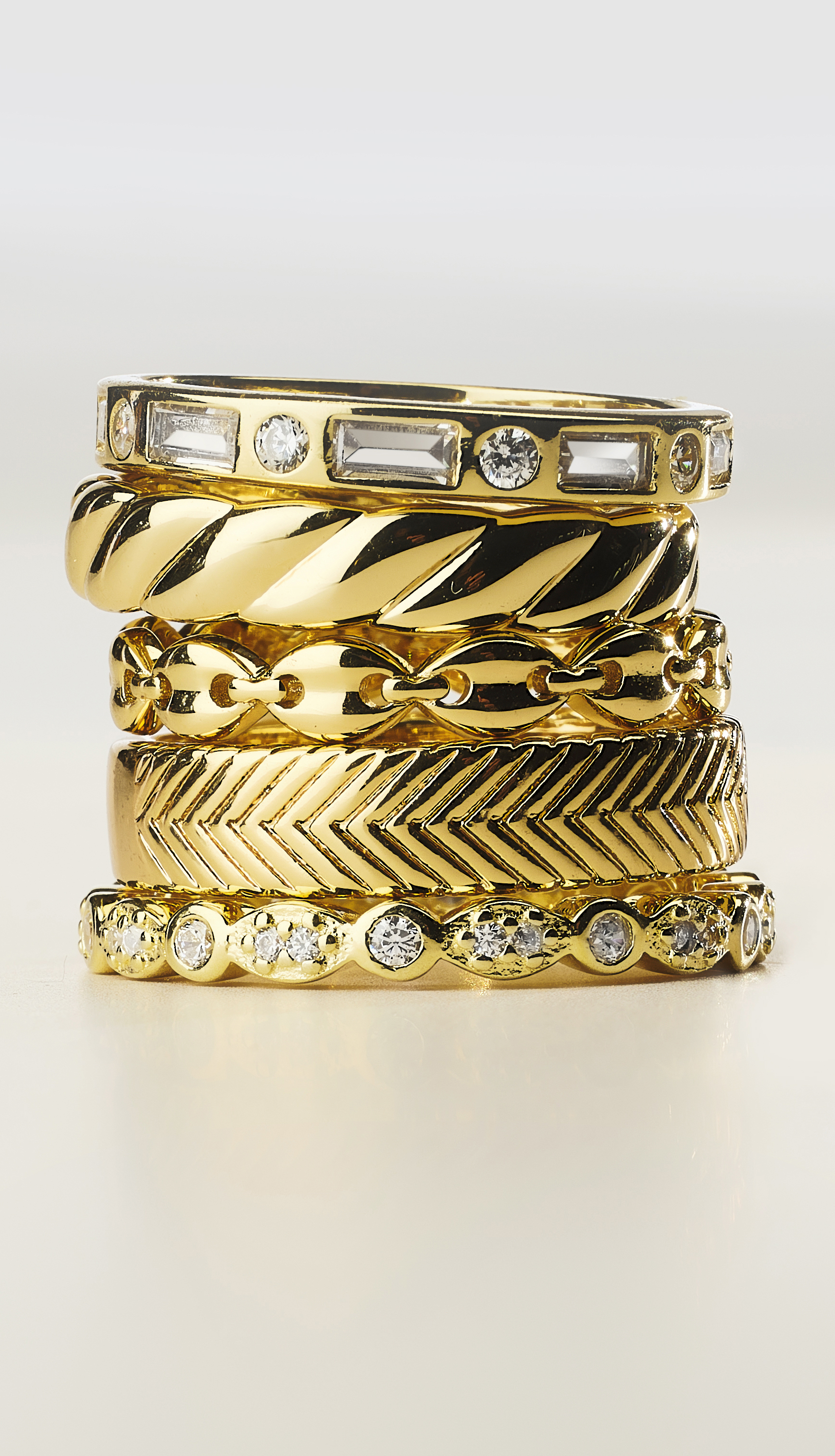 gold and diamond rings in stack on neutral background from low point of view