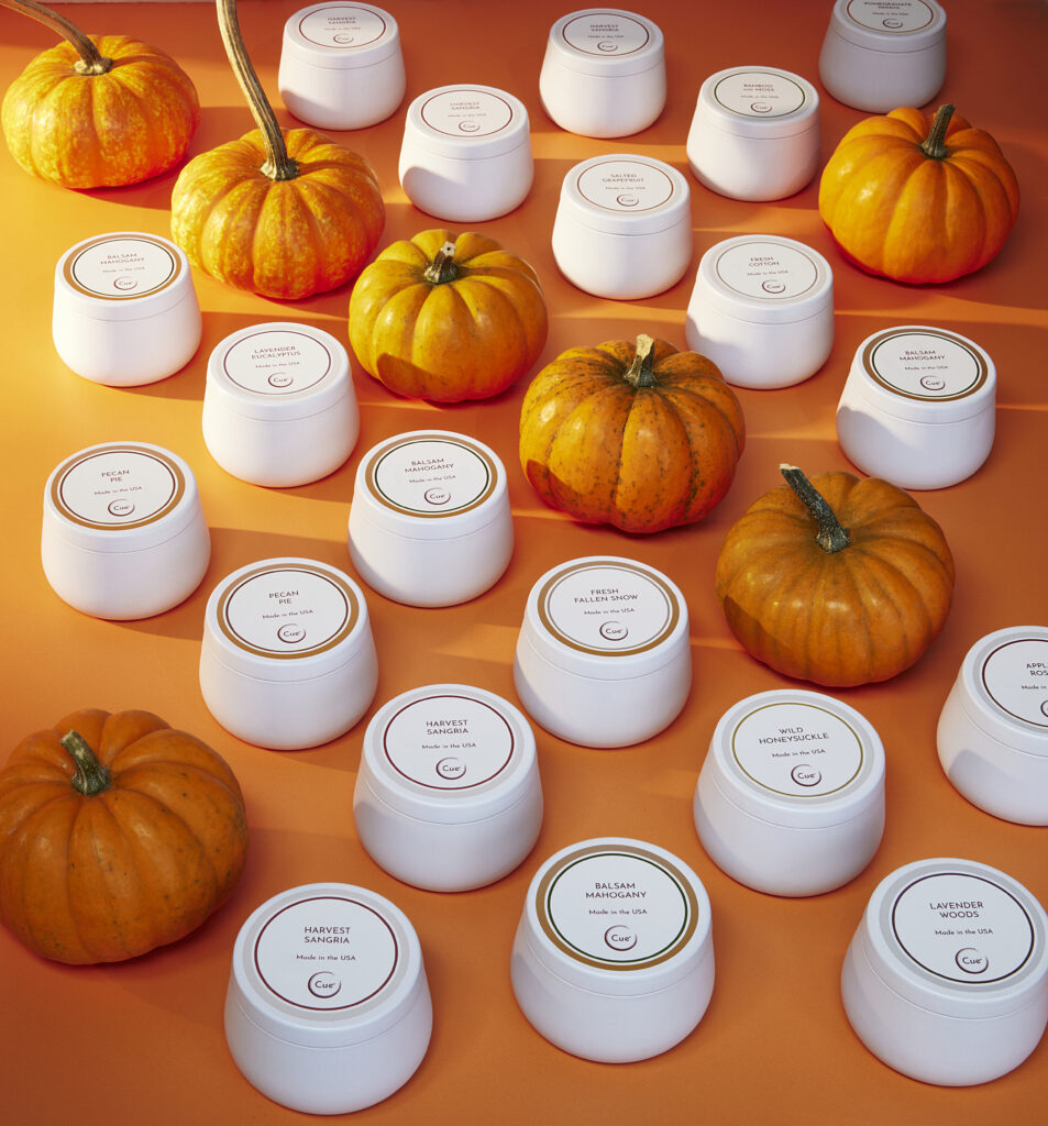 Cue Candle Company white candle tins on orange background with pumpkins