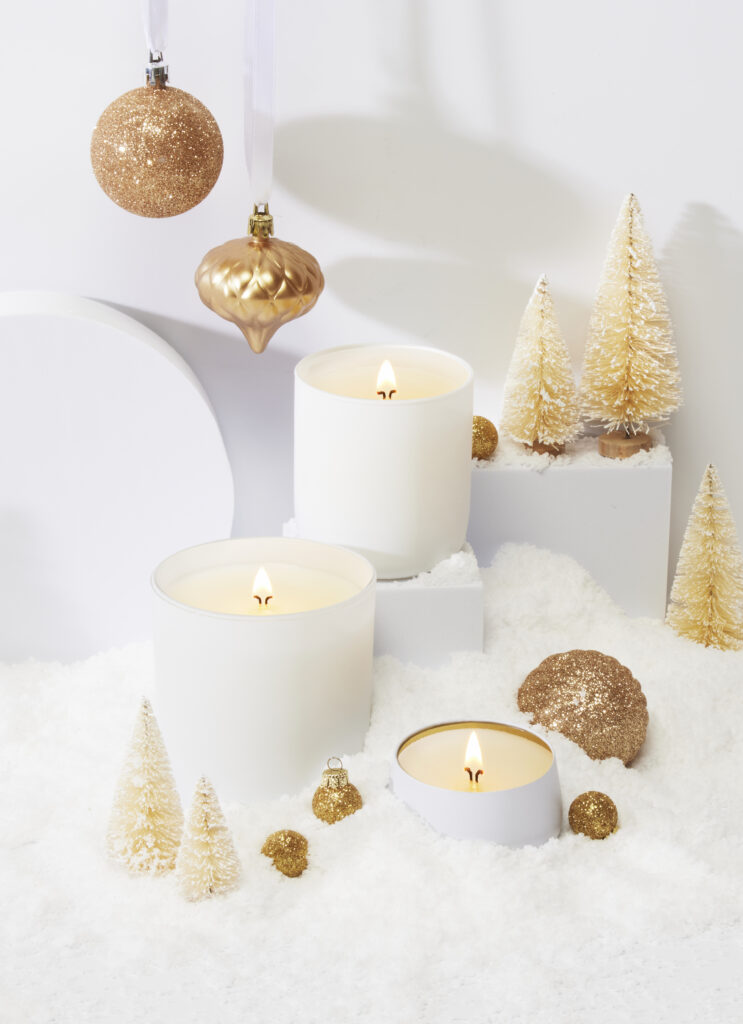 Cue Candle Company white candle jars in white winter scene with gold props