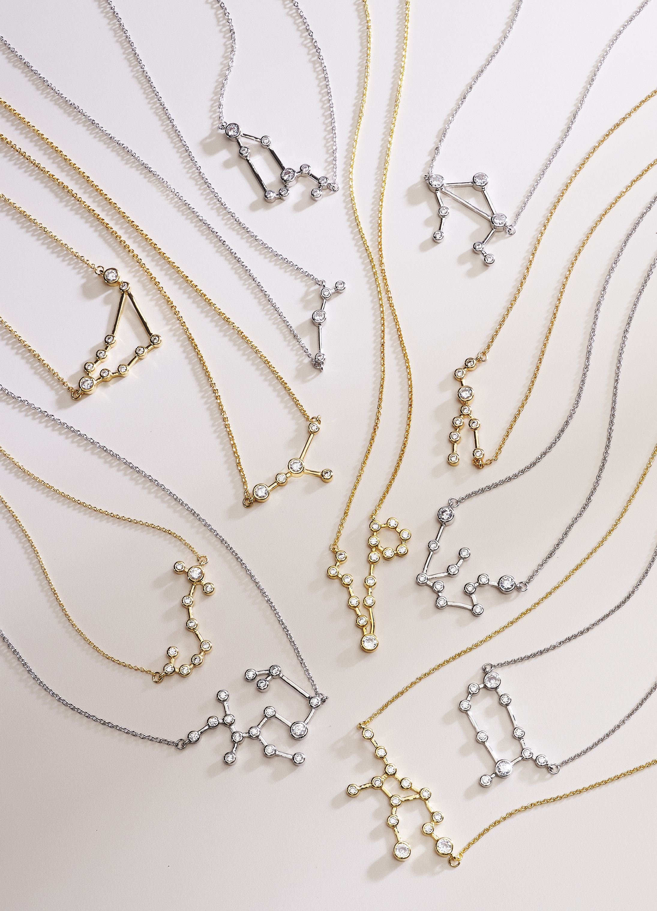 assorted zodiac pendants on neutral colored background with dramatic lighting