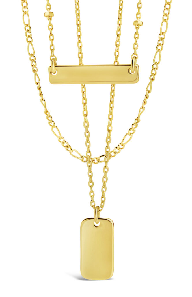 gold layered chains and engraveable pendants on white background