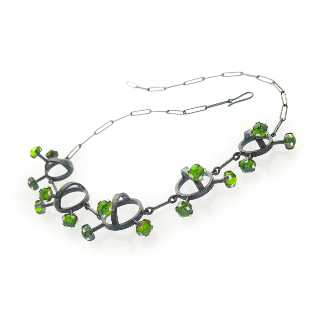 handcrafted necklace with green gems on a white background